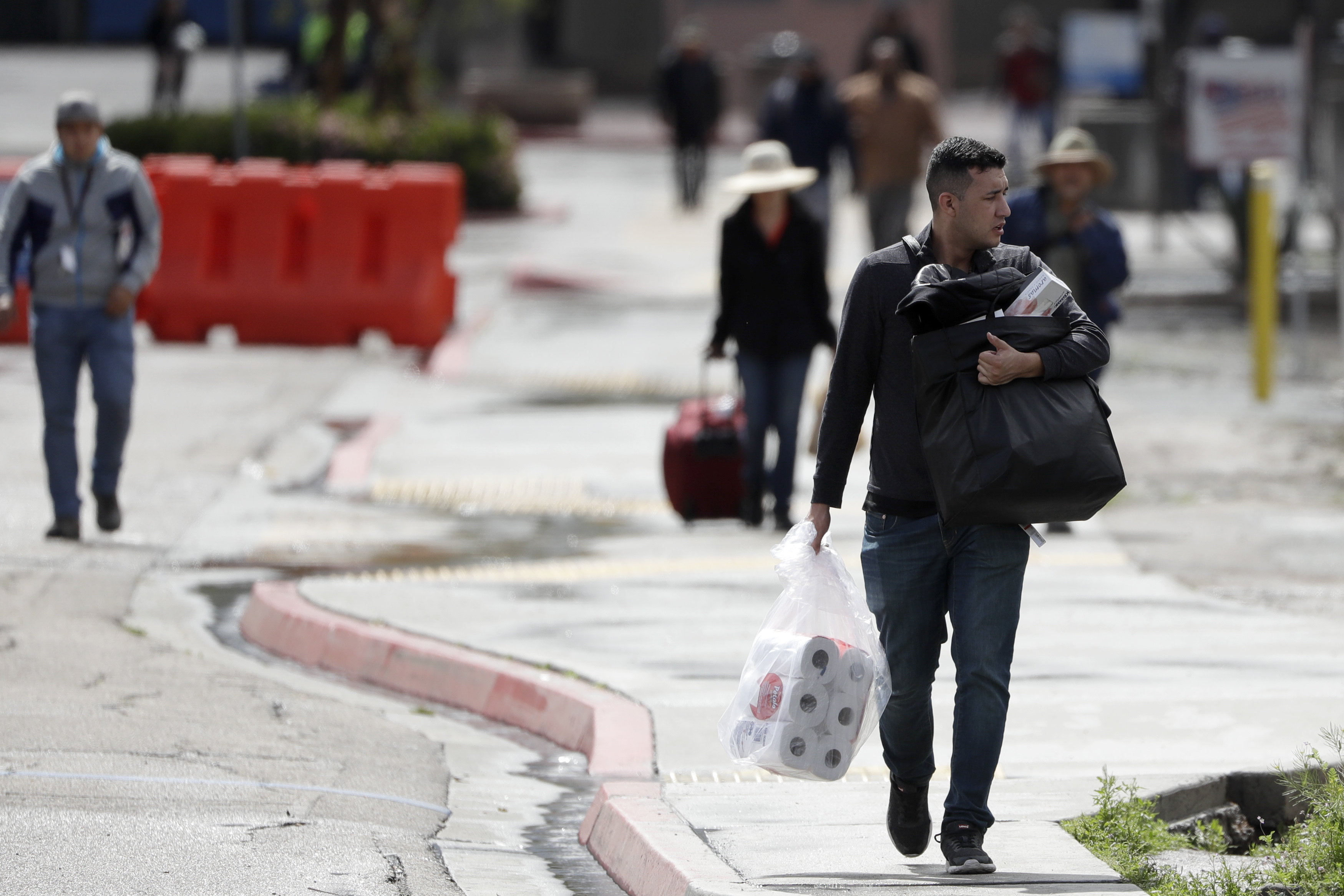 Un hombre lleva papel higiénico después de cruzar la frontera desde Tijuana, México, a San Diego, el miércoles 18 de marzo de 2020, en San Diego.