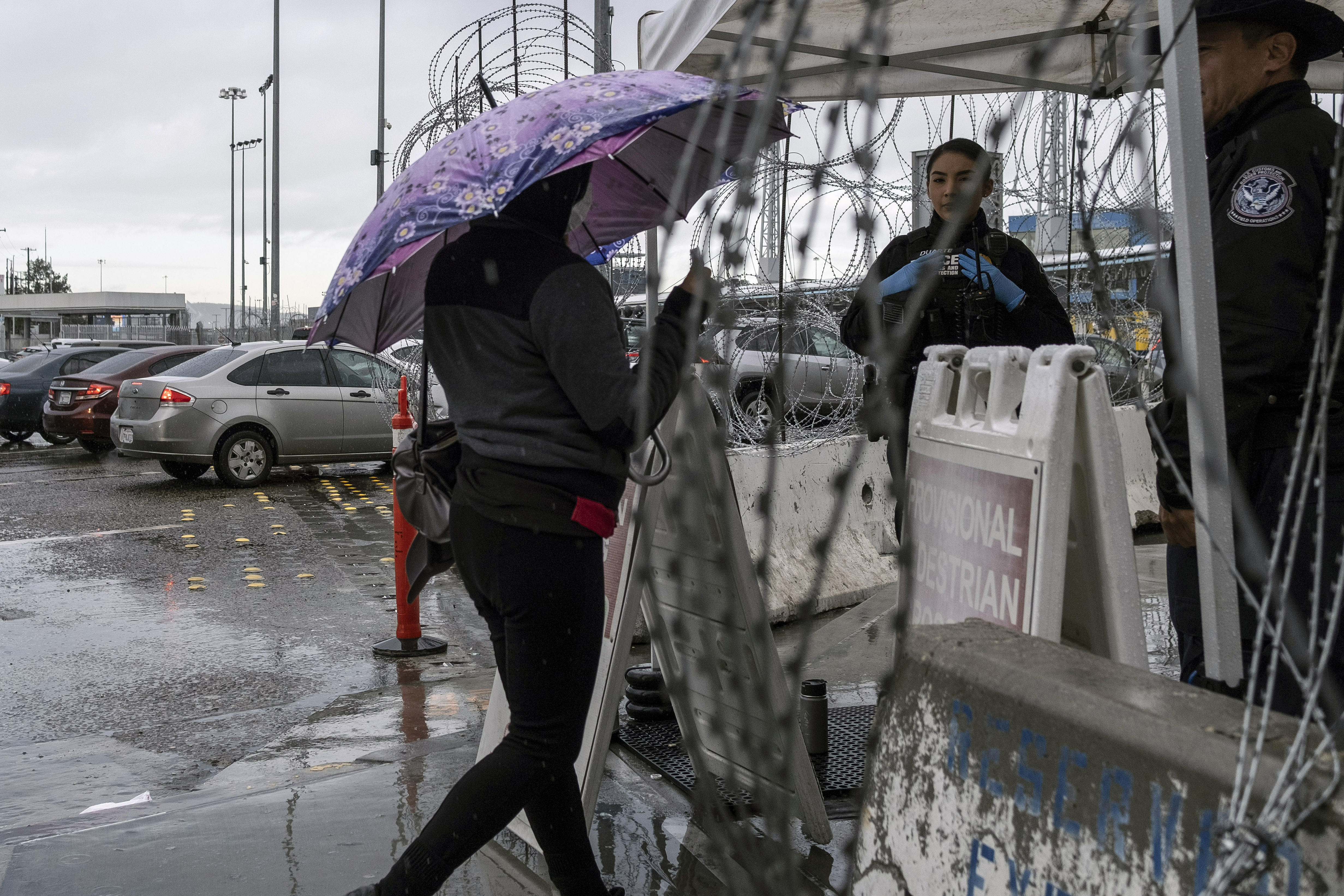 Una mujer que llevaba una máscara protectora muestra su documento a los agentes de Aduanas y Protección Fronteriza en el puerto de entrada de San Ysidro en la frontera entre Estados Unidos y México en Tijuana, estado de Baja California, México, el 19 de marzo de 2020.