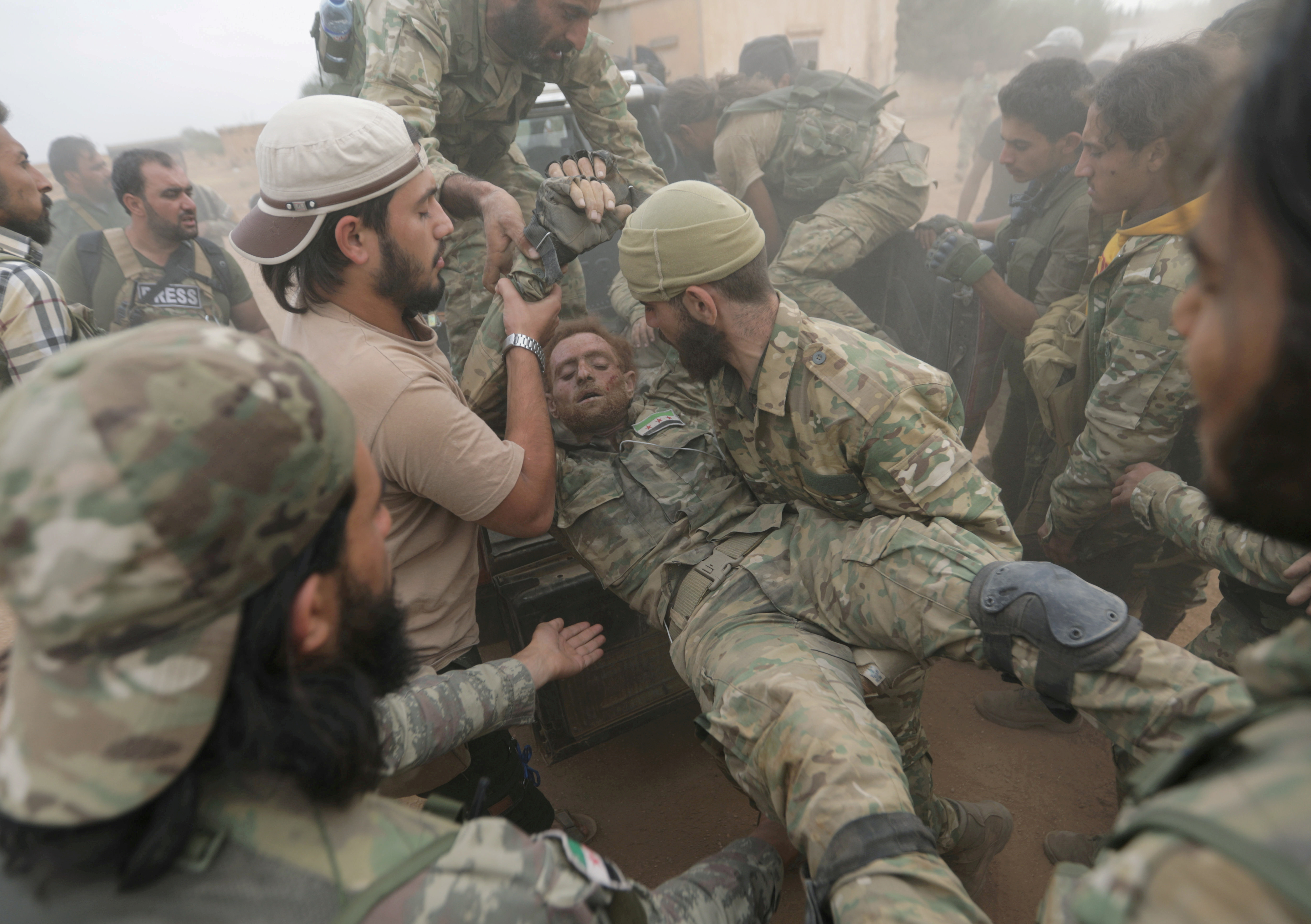 Combatientes rebeldes sirios asisten a su compañero herido cerca de la ciudad fronteriza de Tal Abyad, Siria, el 24 de octubre de 2019 (REUTERS/Khalil Ashawi)