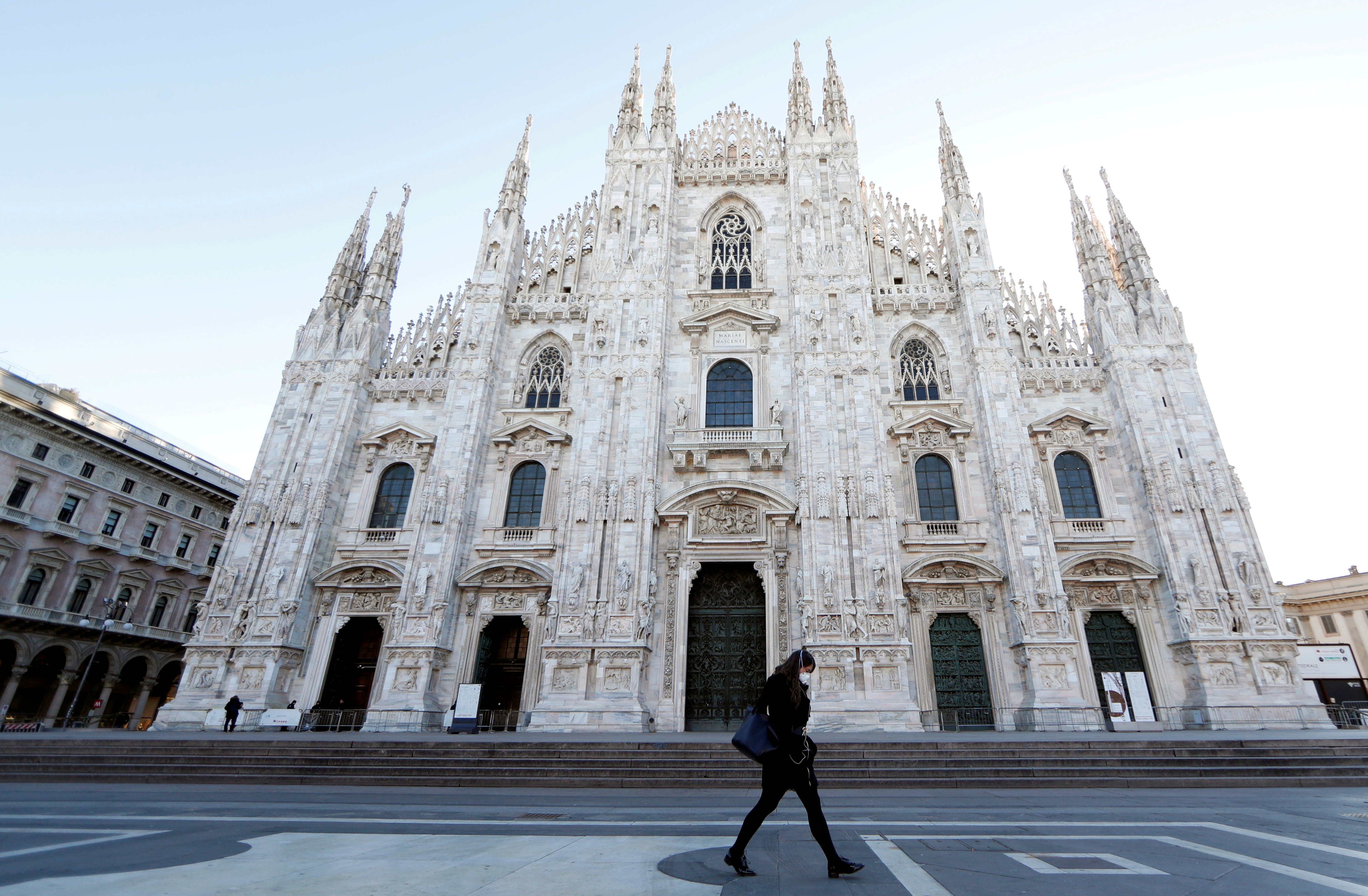 Una mujer con barbijo camina por la plaza del Duomo, en Milán, Italia, el 27 de febrero de 2020. (REUTERS/Yara Nardi)