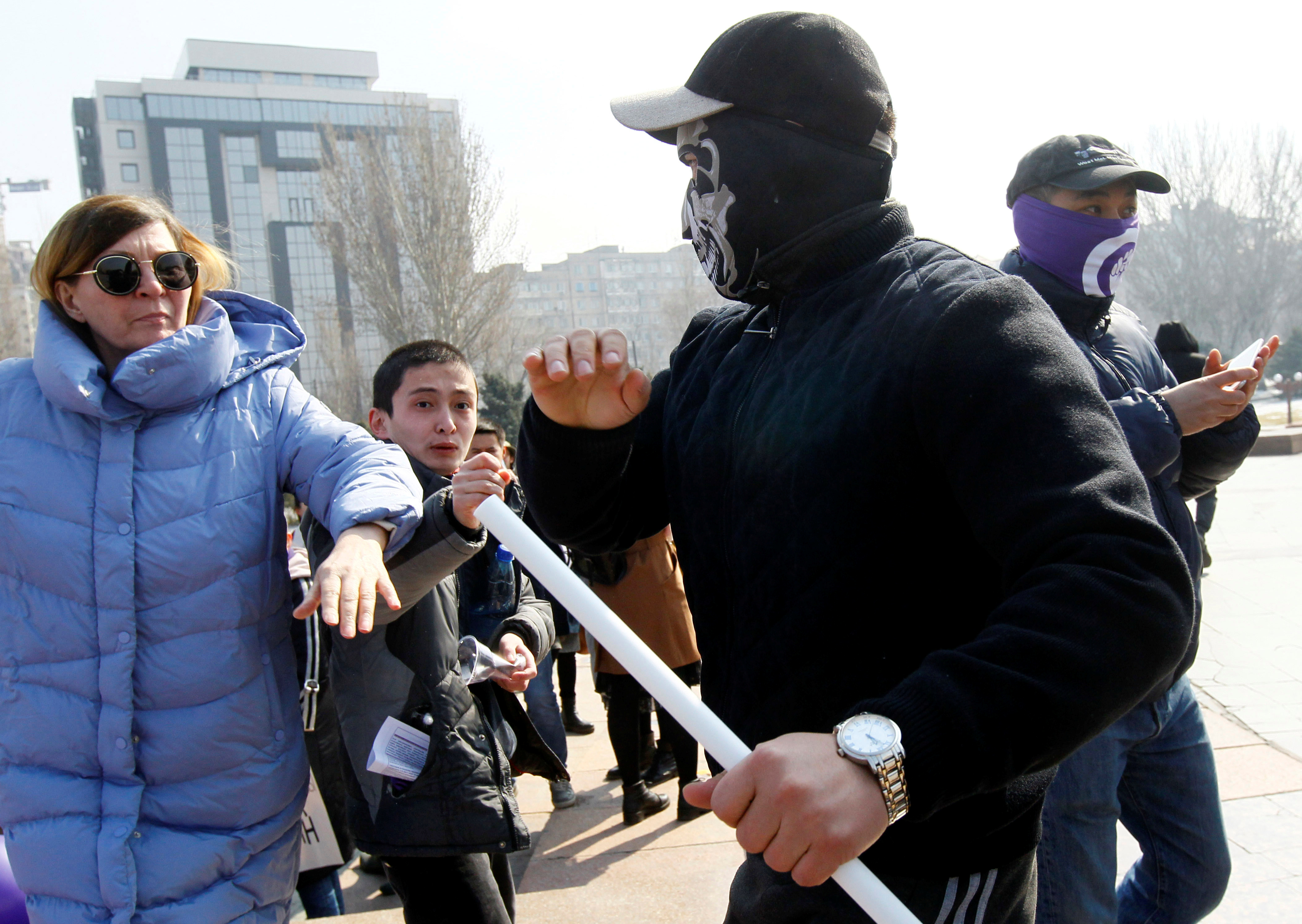 Un hombre con una máscara ataca a una mujer durante una marcha en Bishkek, Kirguistán (REUTERS/Vladimir Pirogov)