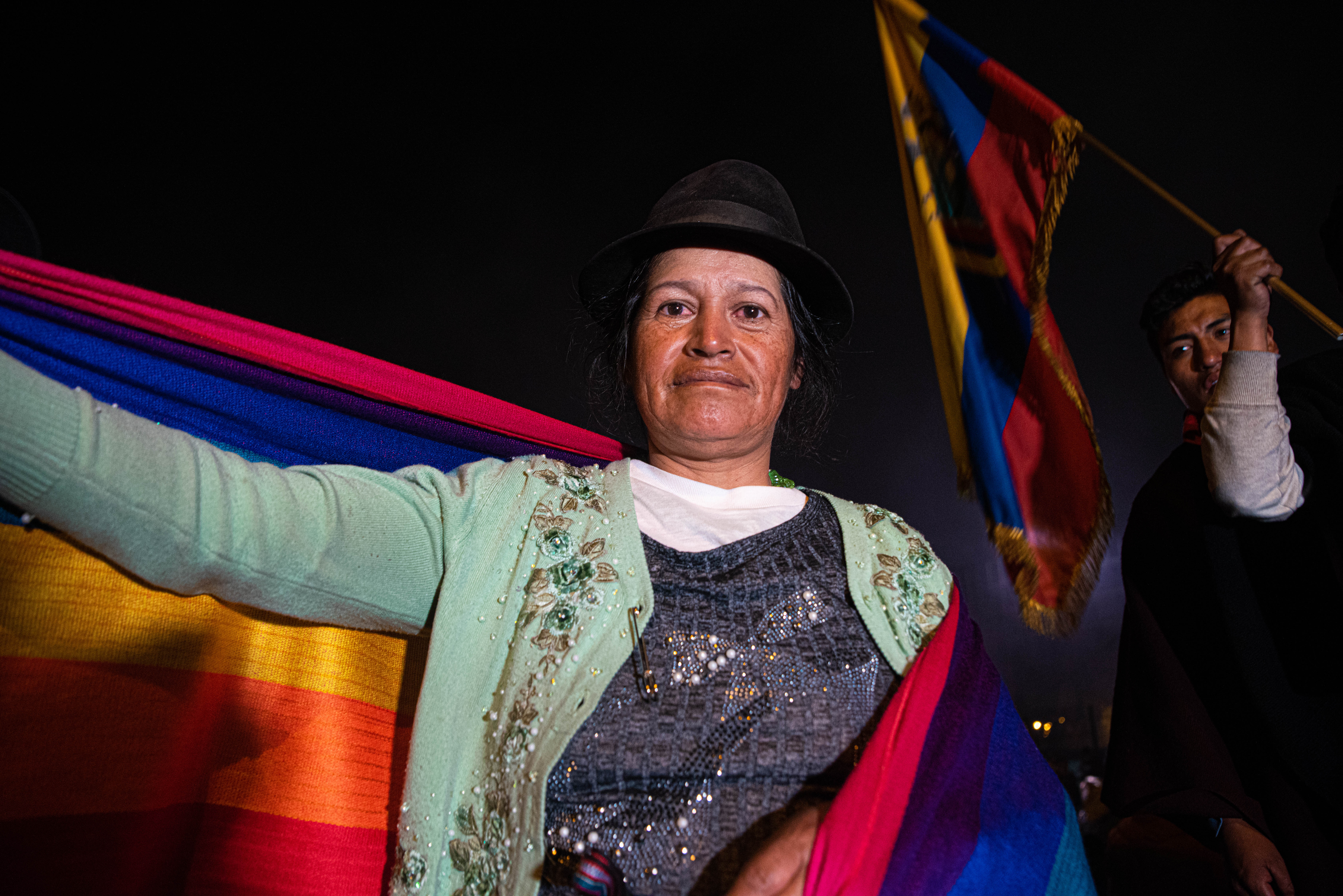 Una mujer indígena celebra con la bandera de Ecuador en sus hombros