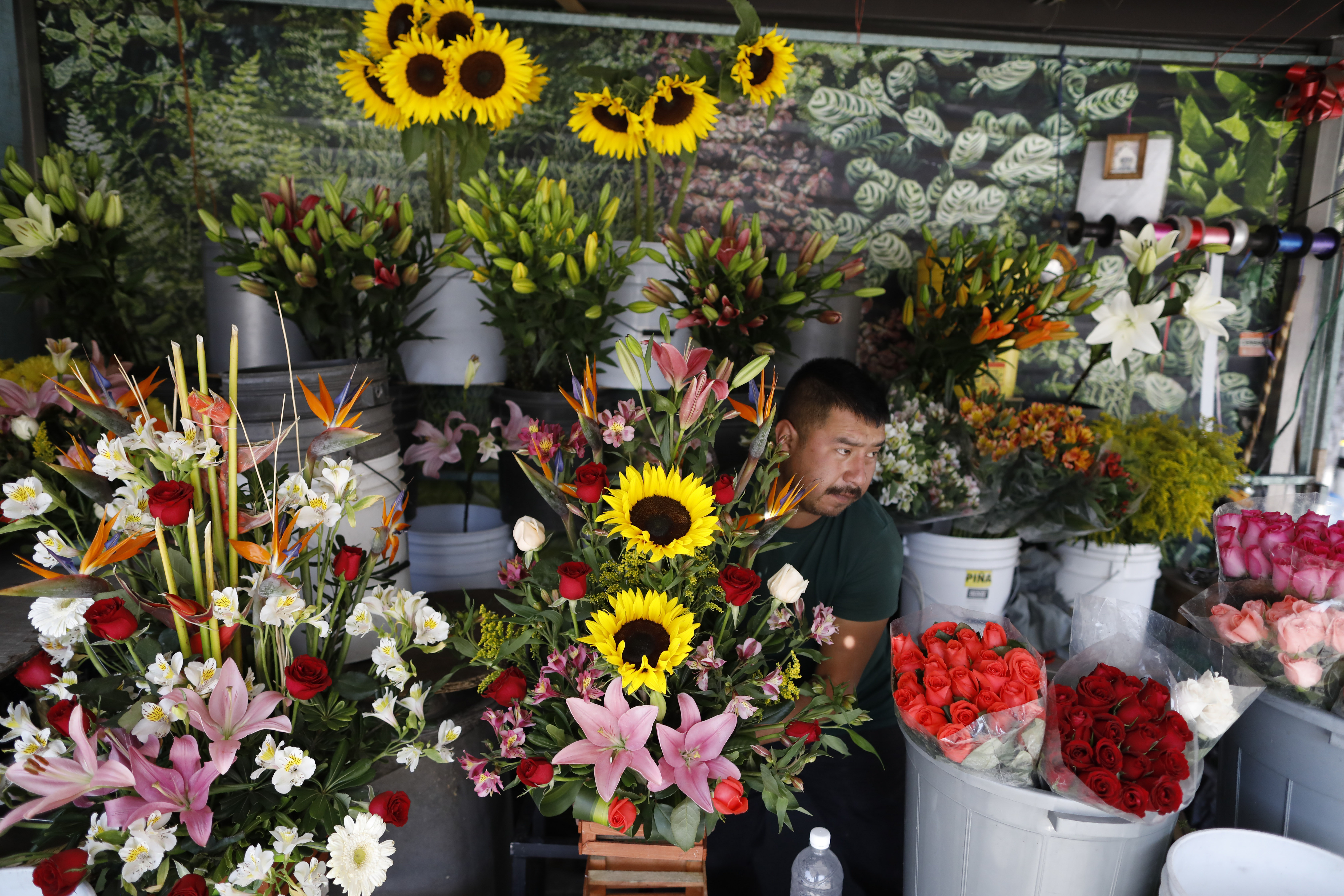 Un vendedor de flores que prefirió no dar su nombre organiza sus flores para exhibirlas cuando abra su puesto callejero en la Ciudad de México, el miércoles 25 de marzo de 2020.