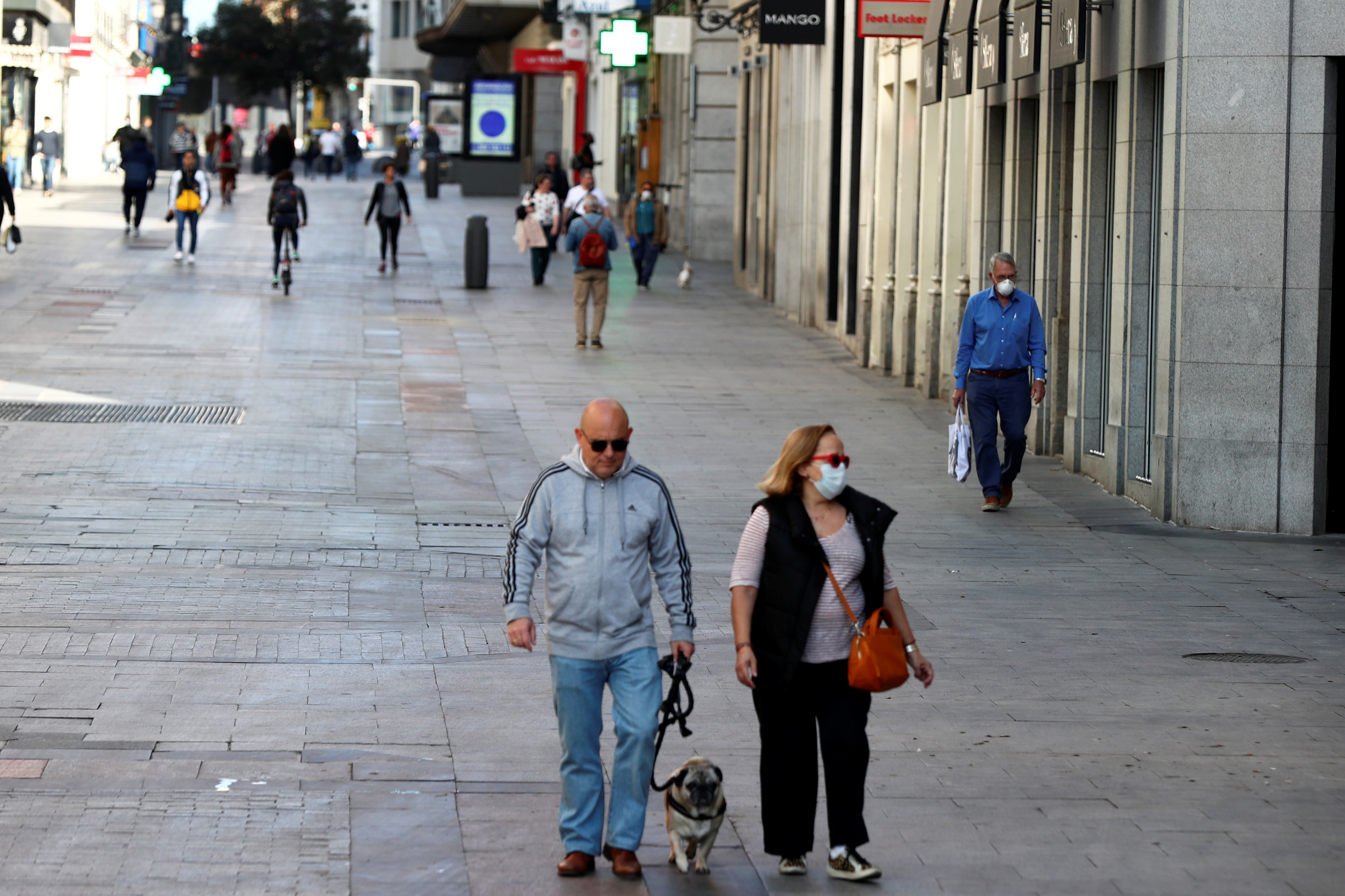 La gente, con máscaras protectoras, camina por una calle vacía debido al brote de coronavirus en el centro de Madrid, España, el 14 de marzo de 2020. REUTERS/Sergio Pérez