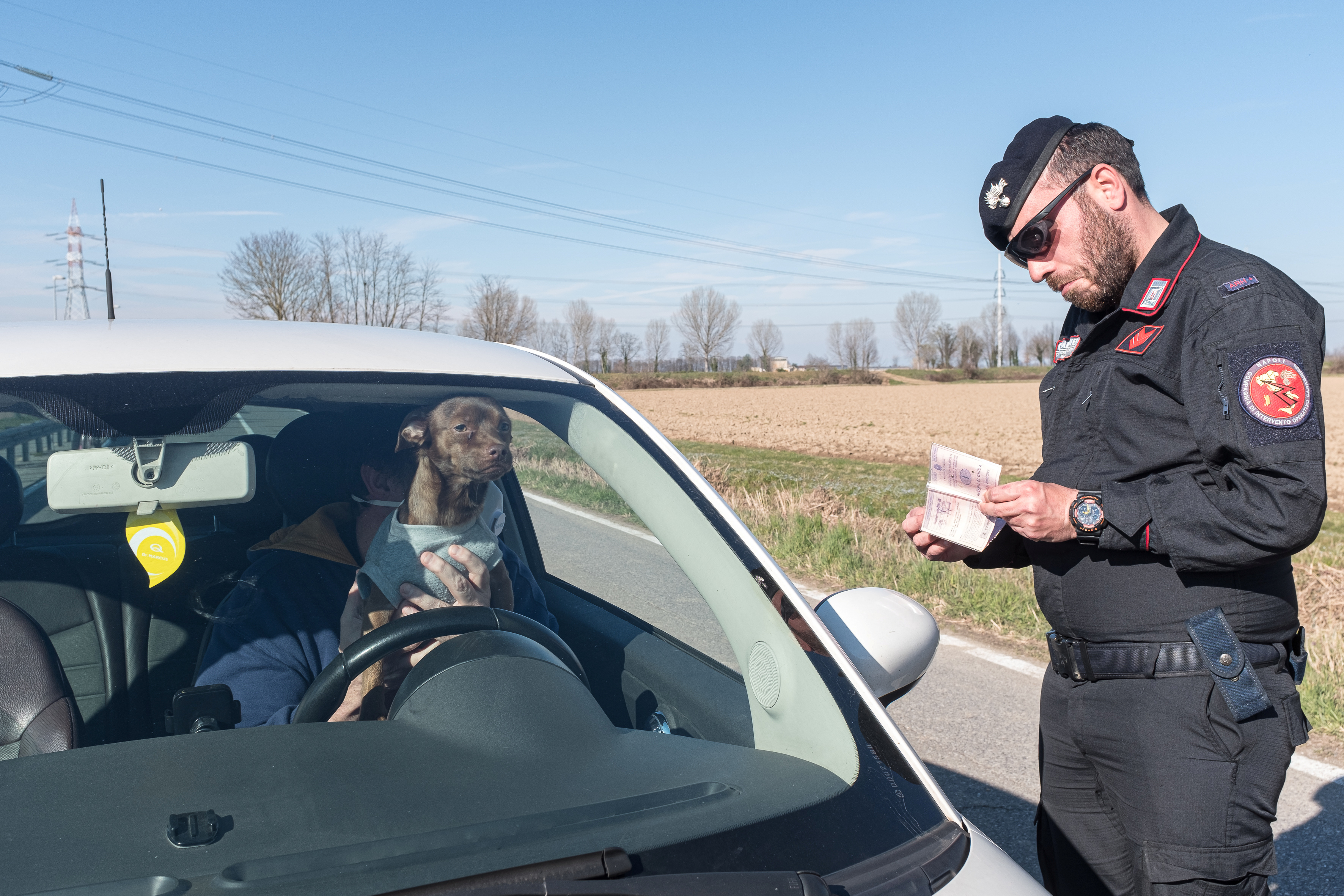 La policía militar de Carabinieri verifica los documentos de un hombre que llevaba una máscara protectora en un automóvil en el puesto de control en San Fiorano, el día 17 de cuarentena en una de las 11 pequeñas ciudades del norte de Italia que ha estado encerrada desde febrero (Marzio Toniolo/via REUTERS)