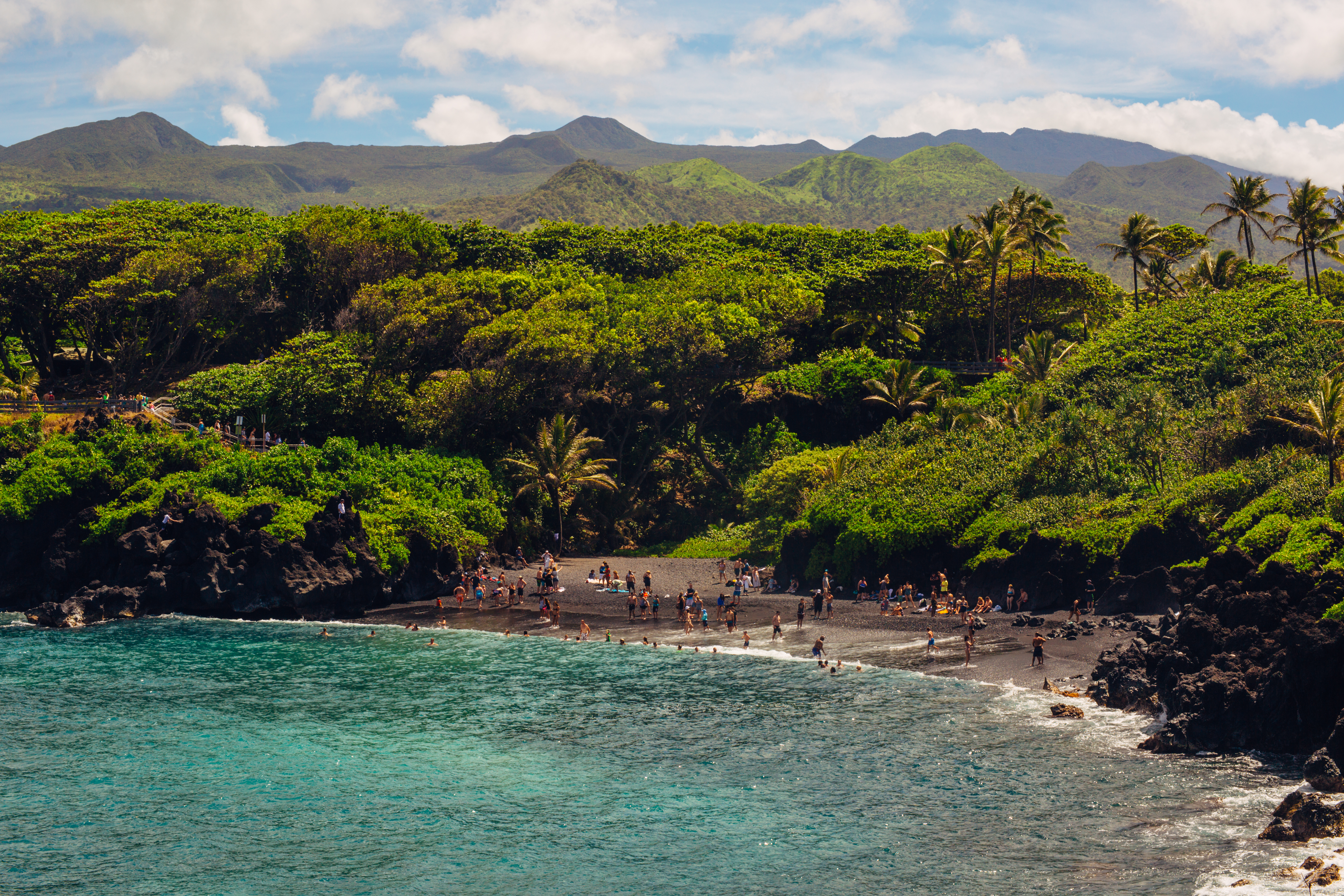 La playa de Honokalani, considerada sagrada por el pueblo hawaiano, es una pequeña media luna volcánica escondida dentro del hermoso parque estatal Waianapanapa en Hawai. Su arena negra como el azabache, el agua turquesa brillante y el frondoso bosque verde se combinan para crear una de las maravillas naturales más impresionantes del mundo