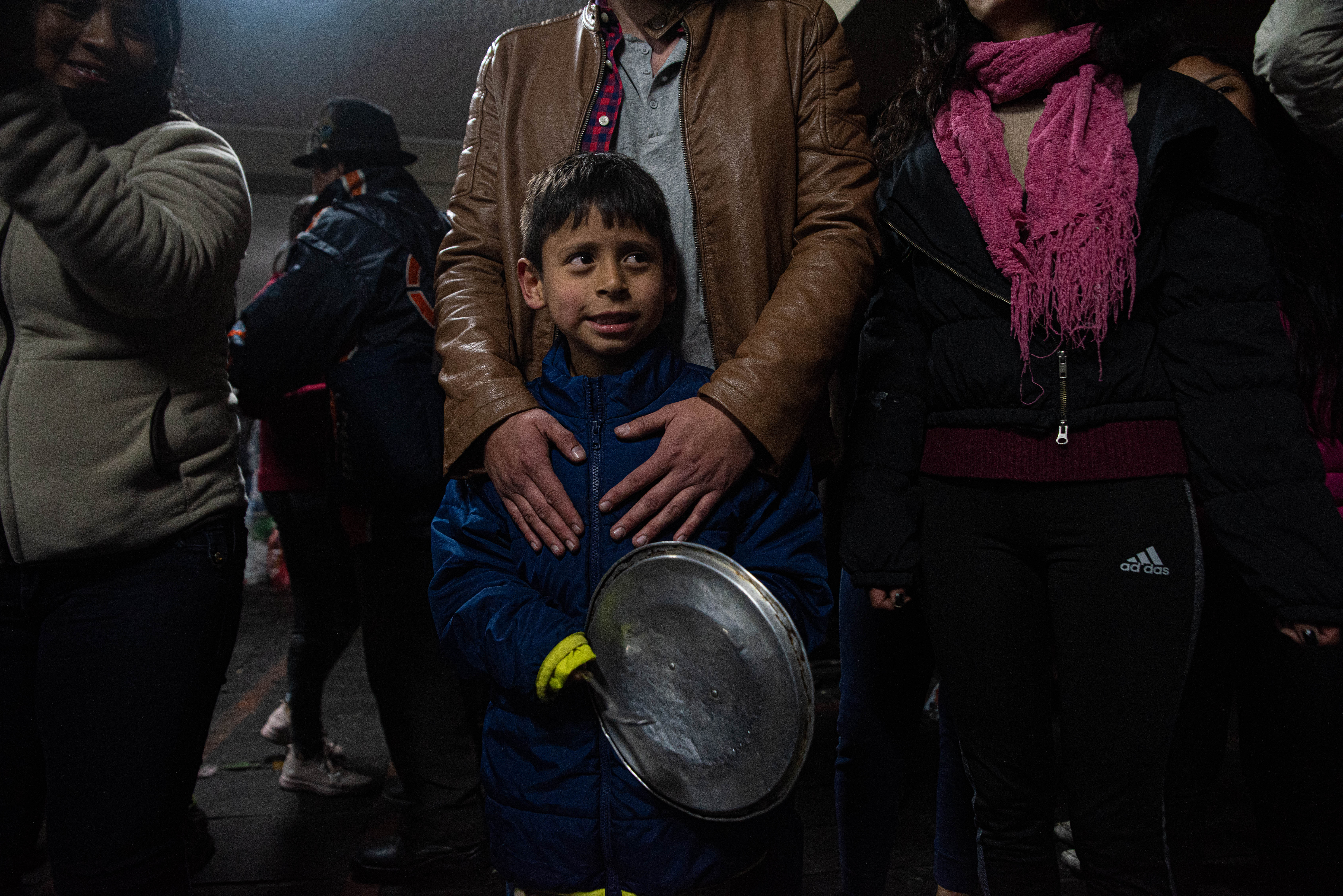 Un niño con su padre golpea la tapa de una cacerola para celebrar durante festejos que se vivieron en Quito en la noche del domingo