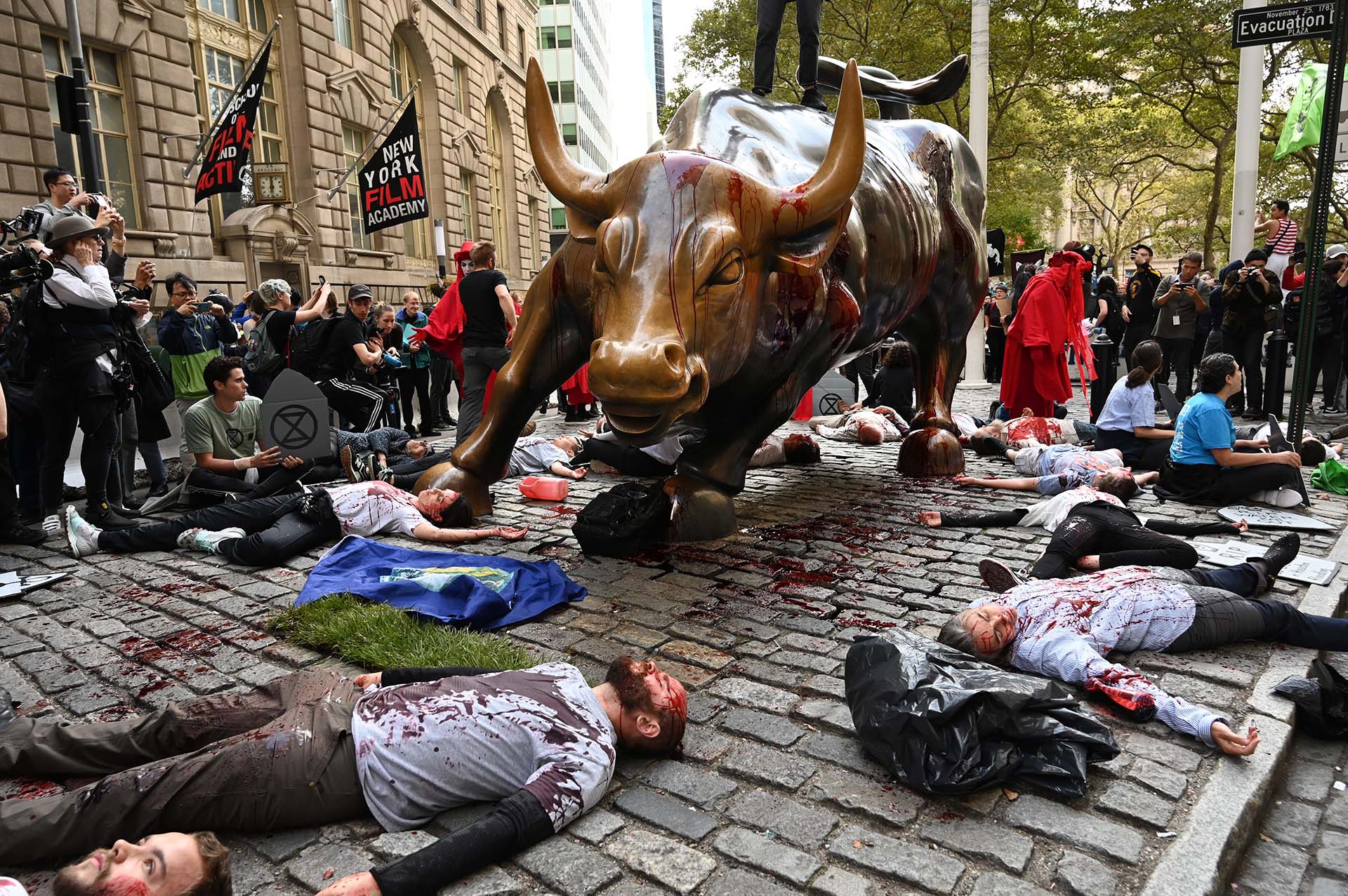 Los manifestantes cubiertos de sangre falsa se reúnen alrededor del Wall Street Bull durante una manifestación de 