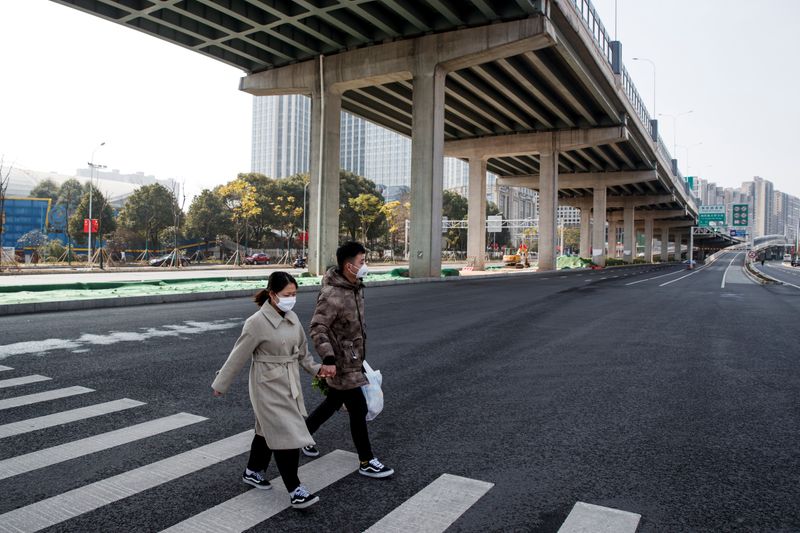 La gente usa máscaras faciales al cruzar una calle principal vacía en Changsha, provincia de Hunan, China, mientras el país es golpeado por un brote de un nuevo coronavirus, el 29 de enero de 2020. REUTERS/Thomas Peter