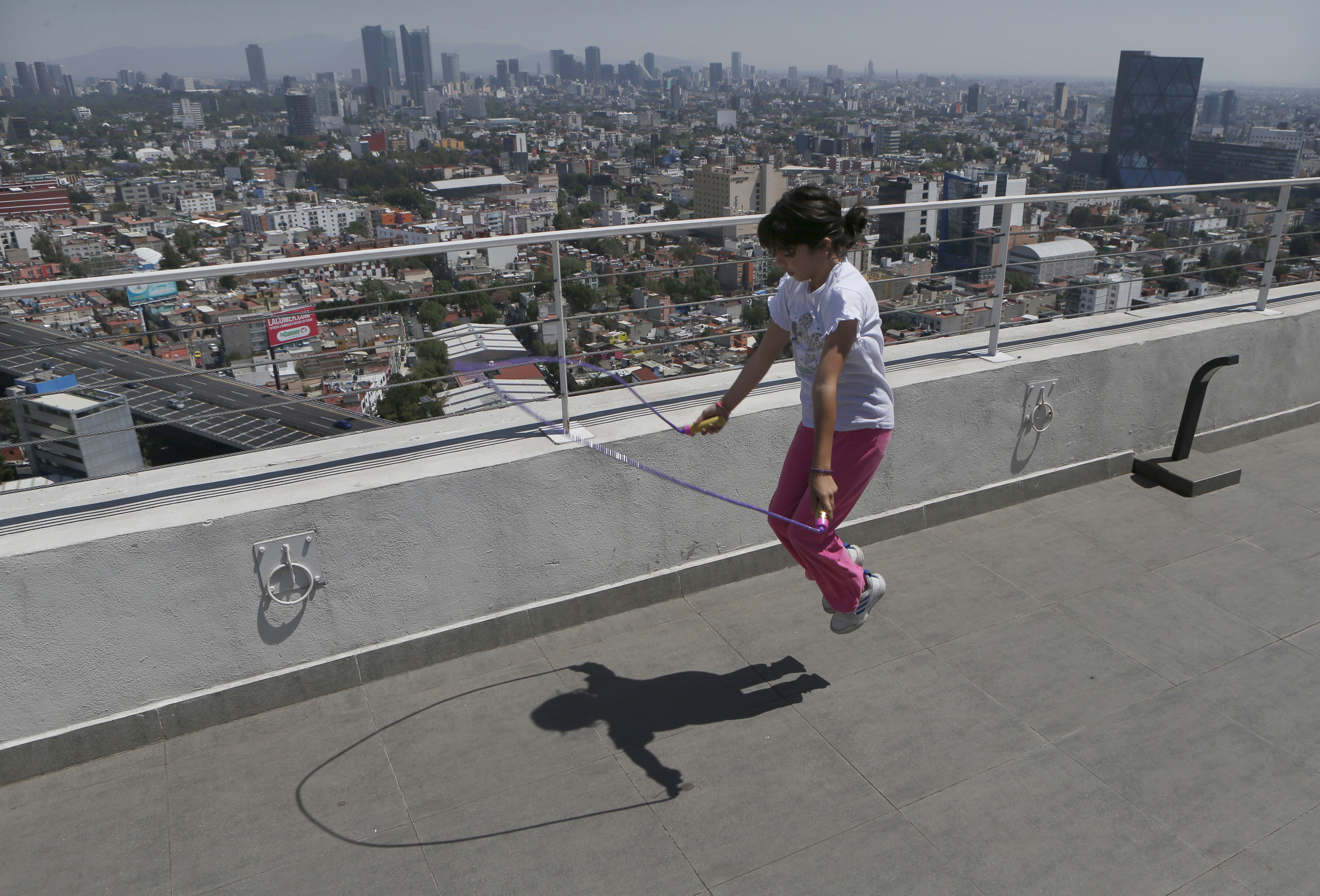 Una niña se queda en casa después de que su escuela canceló las clases debido a la propagación del nuevo coronavirus, Sofía Cortés salta a la cuerda en el techo de un edificio en la Ciudad de México, el martes 31 de marzo de 2020.