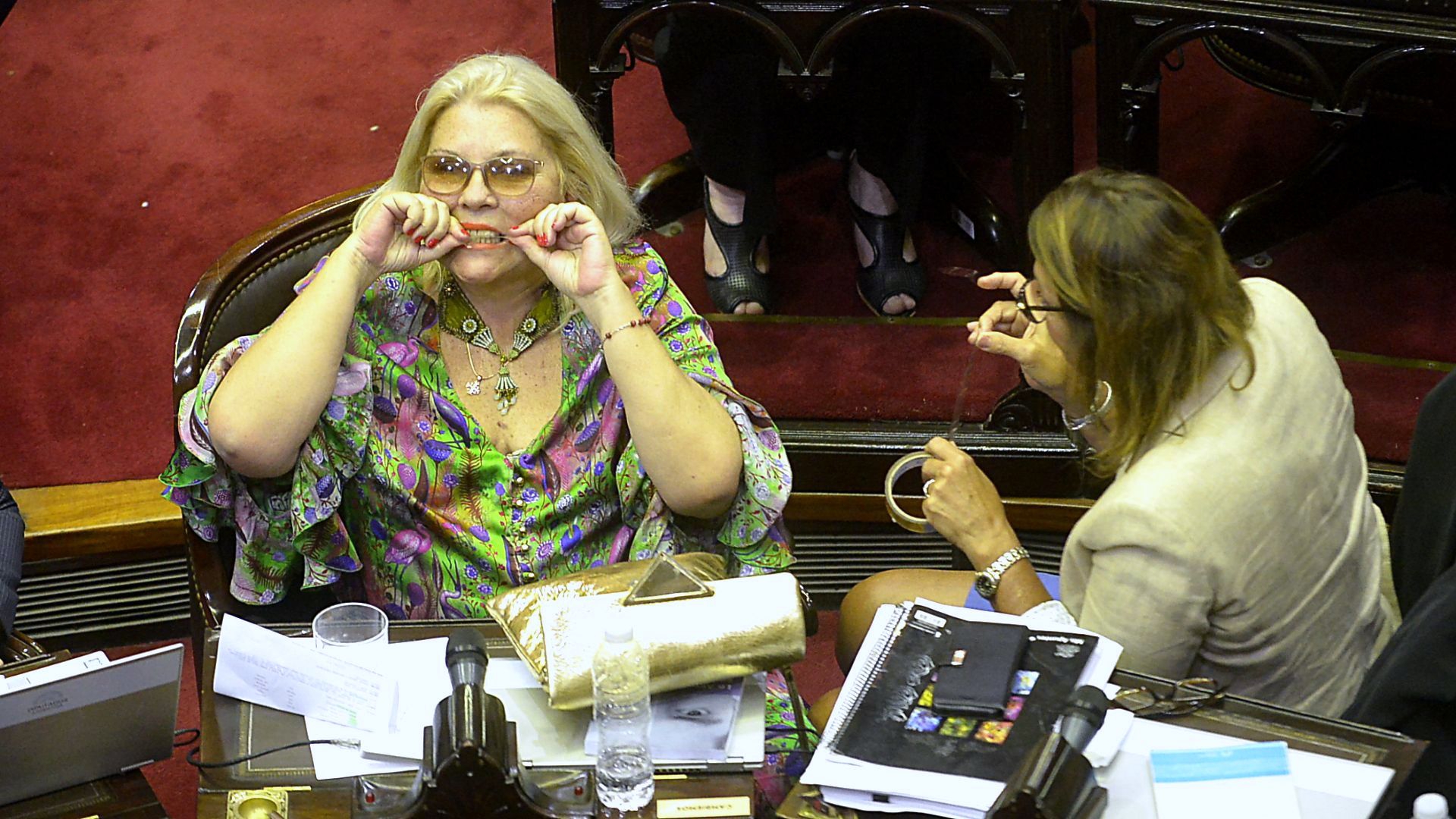 La diputada Elisa "Lilita" Carrio corta un trozo de cinta adhesiva para reparar la rotura de una de las patillas de los lentes de lectura en medio del tratamiento de la ley de presupuesto 2019