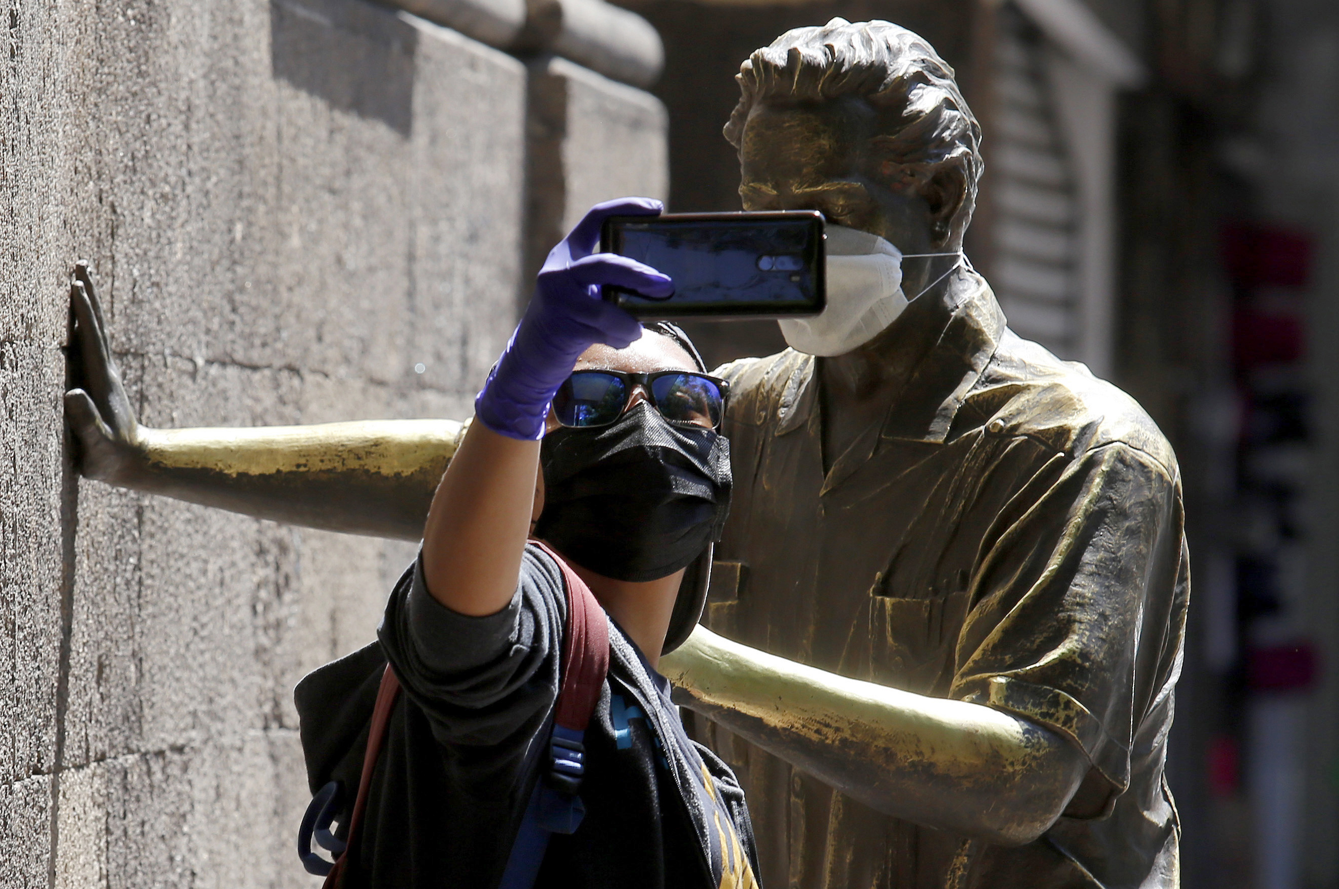 Un hombre se toma una selfie frente a una estatua del ingeniero mexicano Jorge Matute (1912-2002) con una máscara facial, durante la nueva pandemia de coronavirus COVID-19, en Guadalajara, México, el 31 de marzo de 2020.