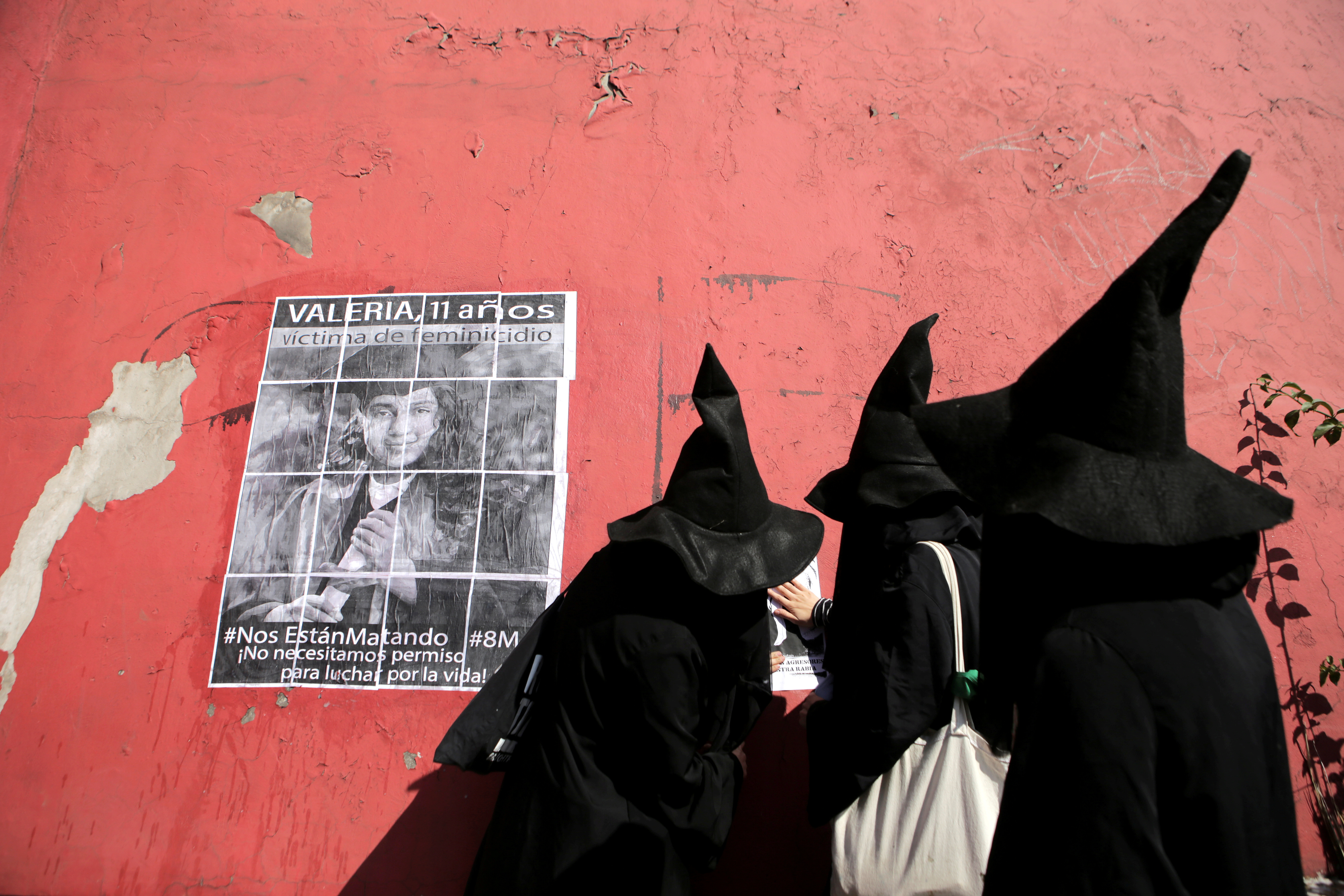 Mujeres vestidas de brujas colocan carteles en una pared durante una marcha para conmemorar el Día Internacional de la Mujer en Ciudad Nezahualcóyotl, en las afueras de la Ciudad de México (REUTERS / Raquel Cunha)