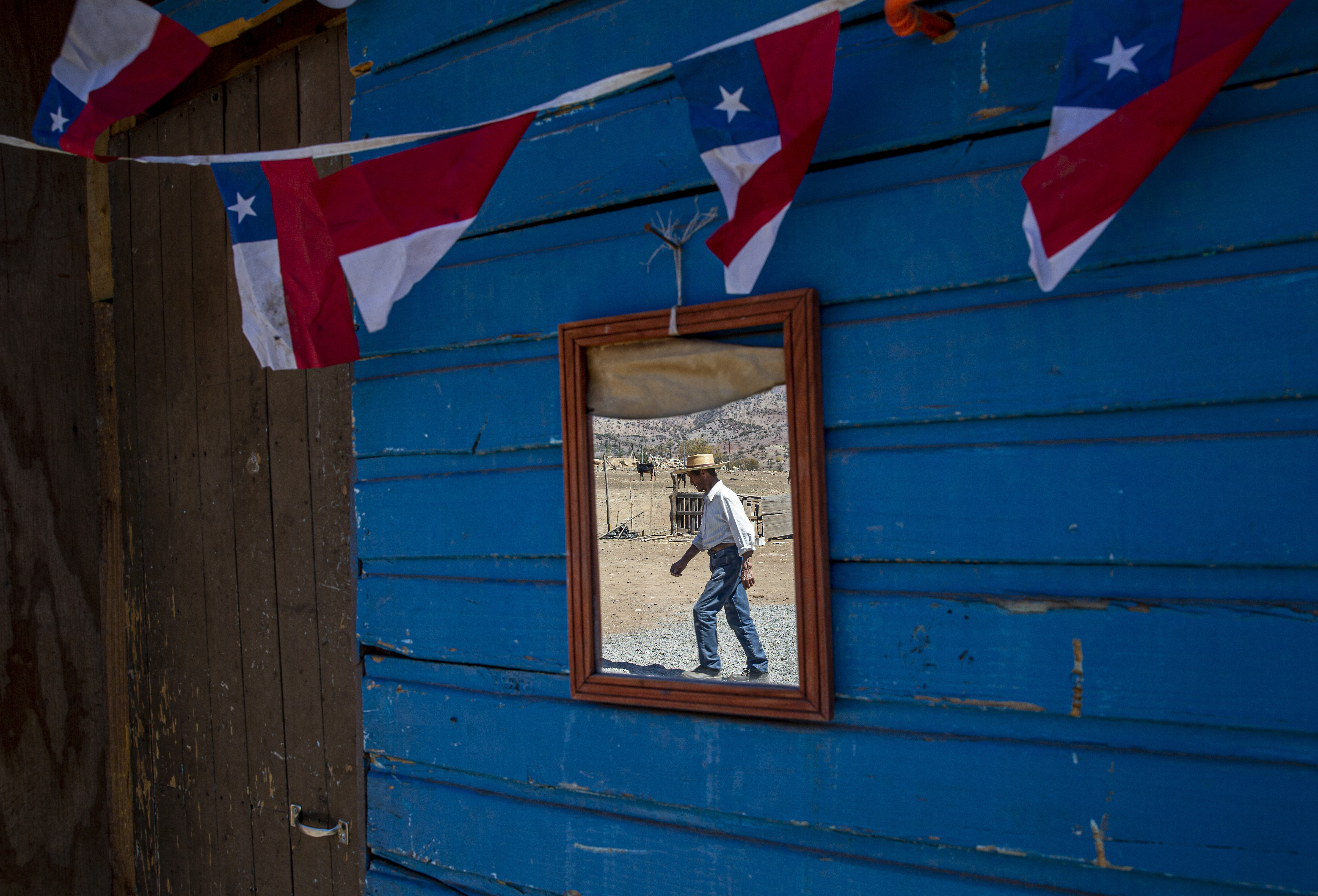 El ganadero Benito Morena se refleja mientras camina en un espejo de su rancho. Desde la región de Coquimbo en el norte de Chile hasta Maule en el sur, más de 30.000 cabezas de ganado han muerto por hambre o sed, y los cultivos se han perdido por falta de lluvias, de acuerdo con el Ministerio de Agricultura