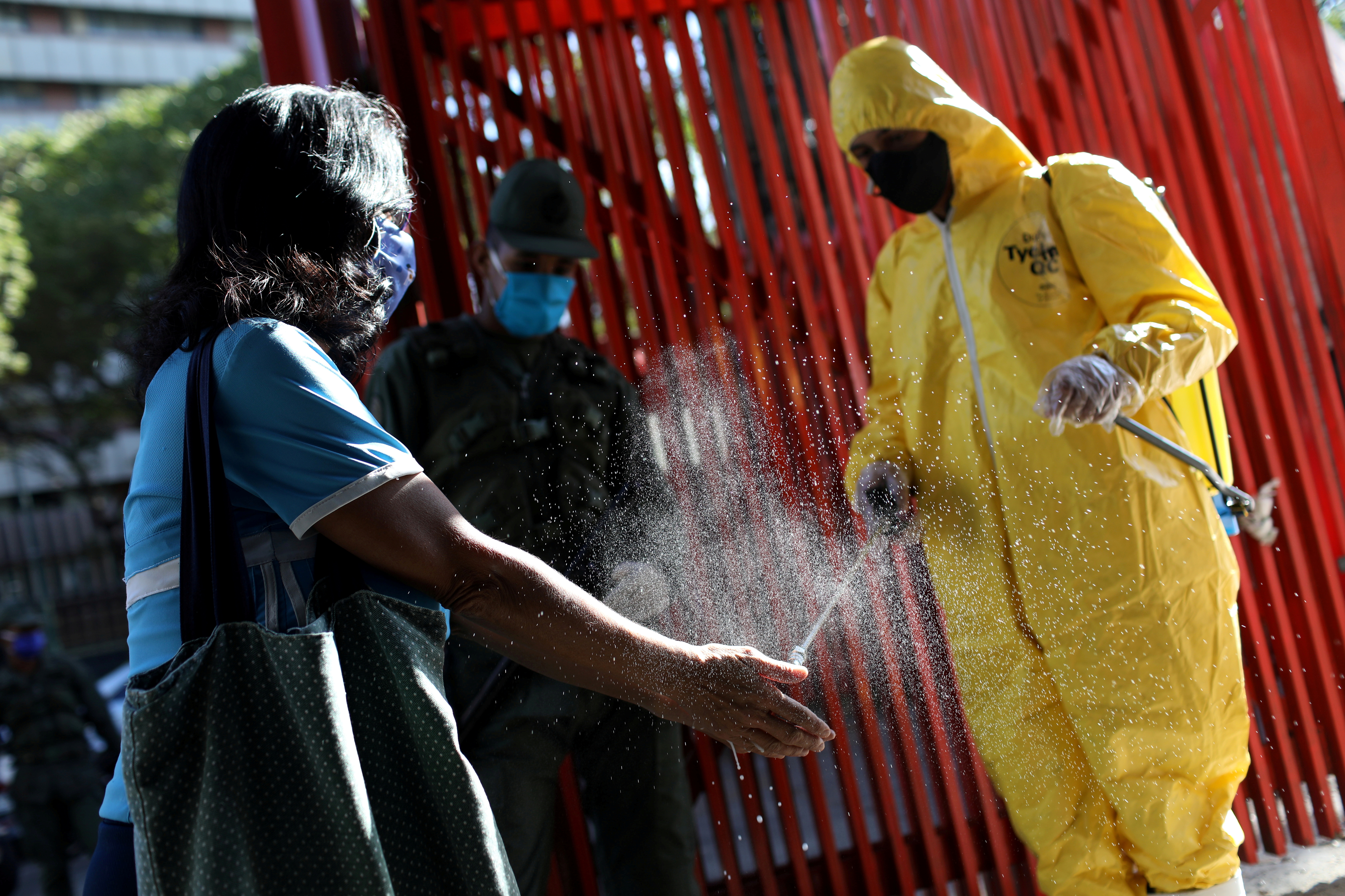 Un trabajador limpia las manos de una venezolana en Caracas (REUTERS/Manaure Quintero)