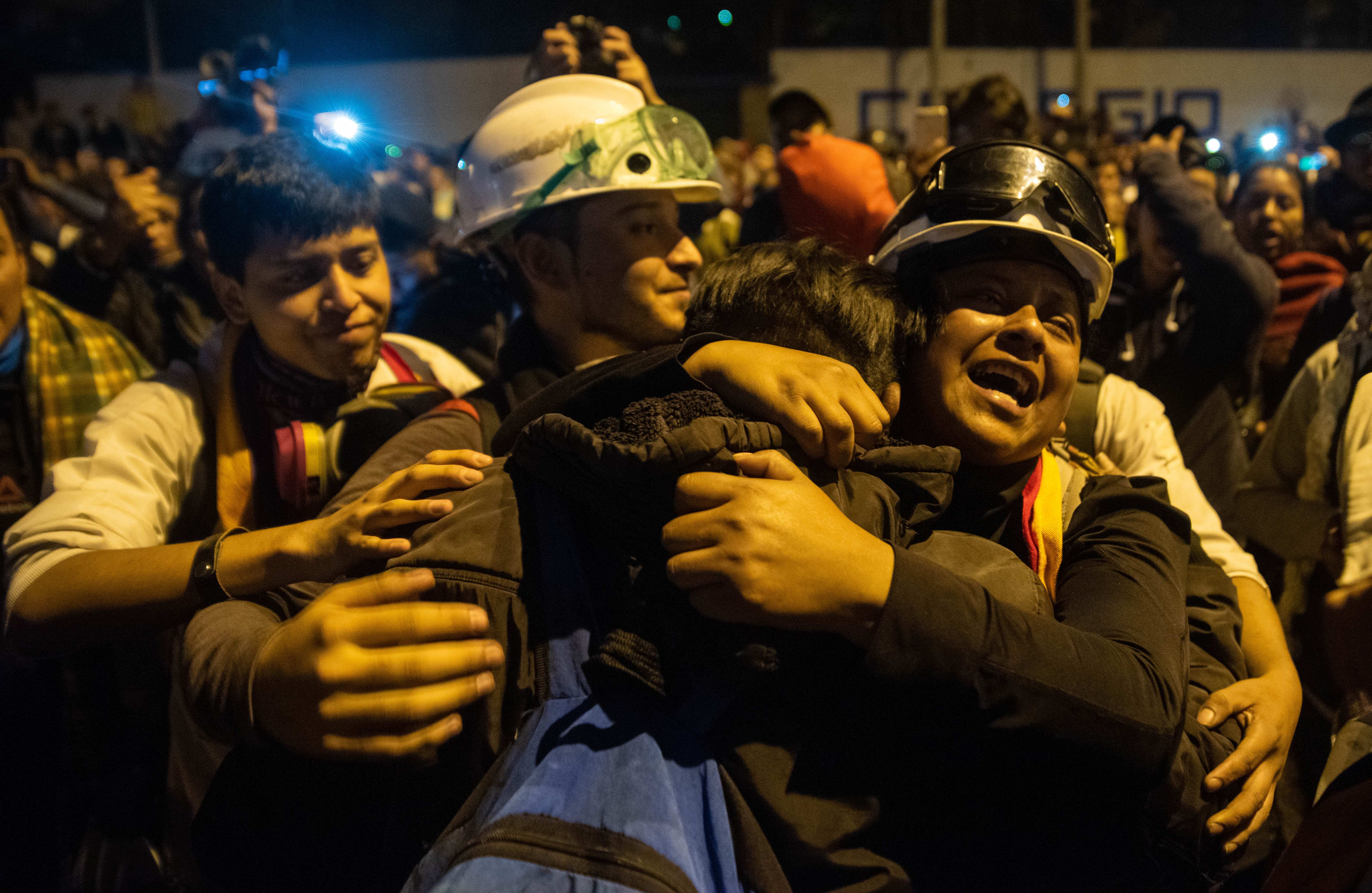 Manifestantes con chalecos y cascos se abrazan en las calles de Quito, Ecuador