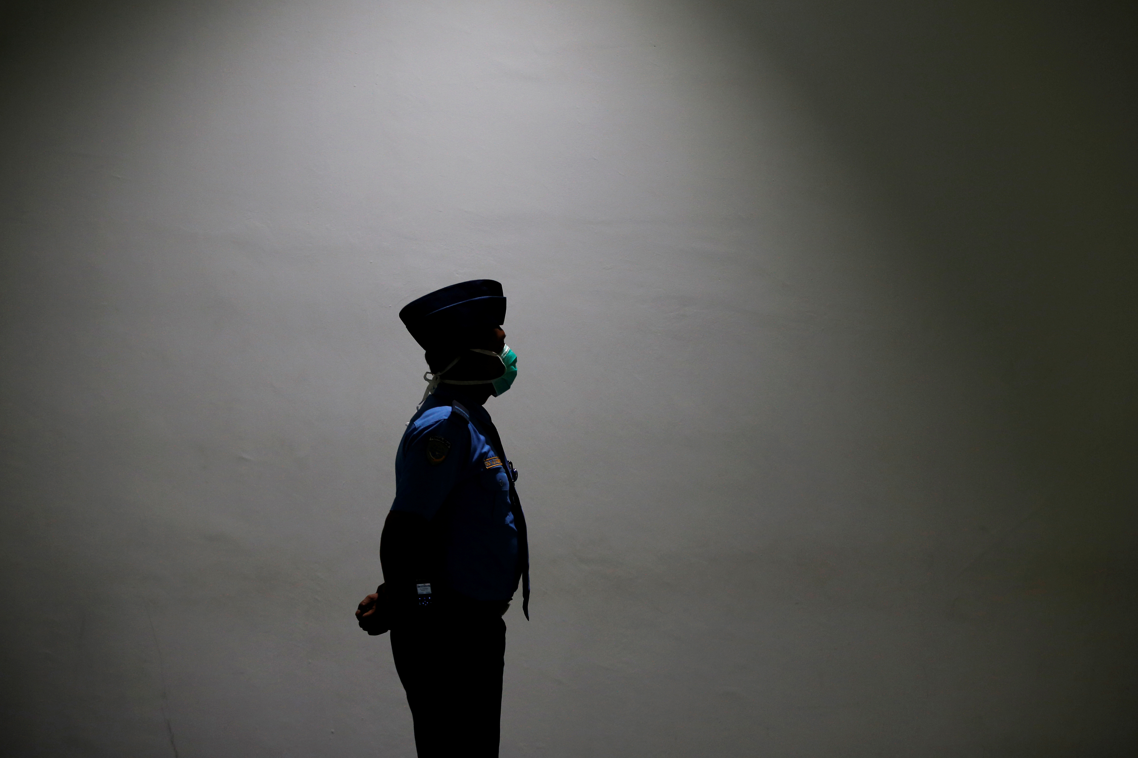 Un oficial de seguridad de aviación con máscara médica está de pie mientras protege en la terminal de llegadas internacionales del aeropuerto Soekarno Hatta cerca de Yakarta, Indonesia, el 21 de enero de 2020. REUTERS / Willy Kurniawan