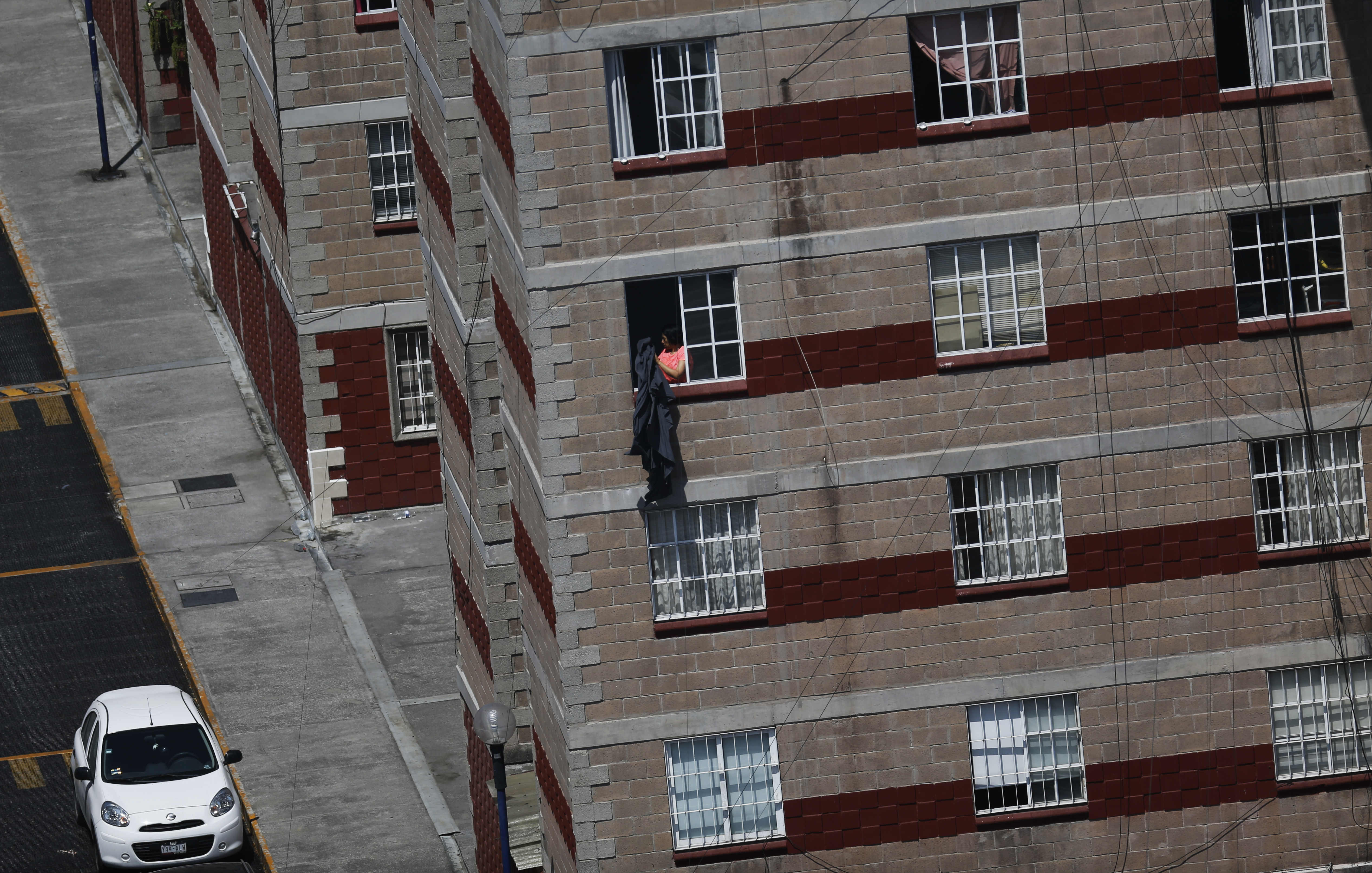 Una persona sacude una manta desde la ventana de su departamento en la Ciudad de México, el martes 31 de marzo de 2020.