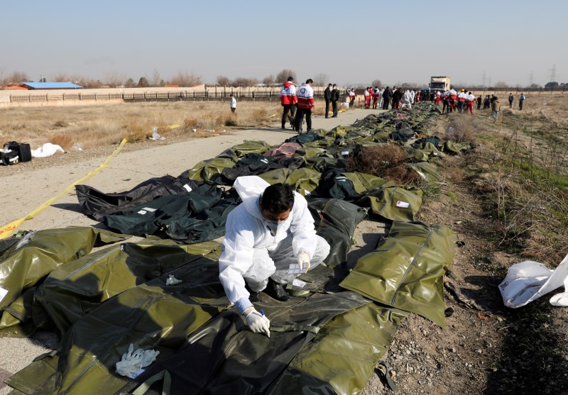 Cuerpos de pasajeros en bolsas de plástico en el sitio donde el avión de Ukraine International Airlines se estrelló después del despegue del aeropuerto iraní Imán Jomeini, en las afueras de Teherán (Reuters)