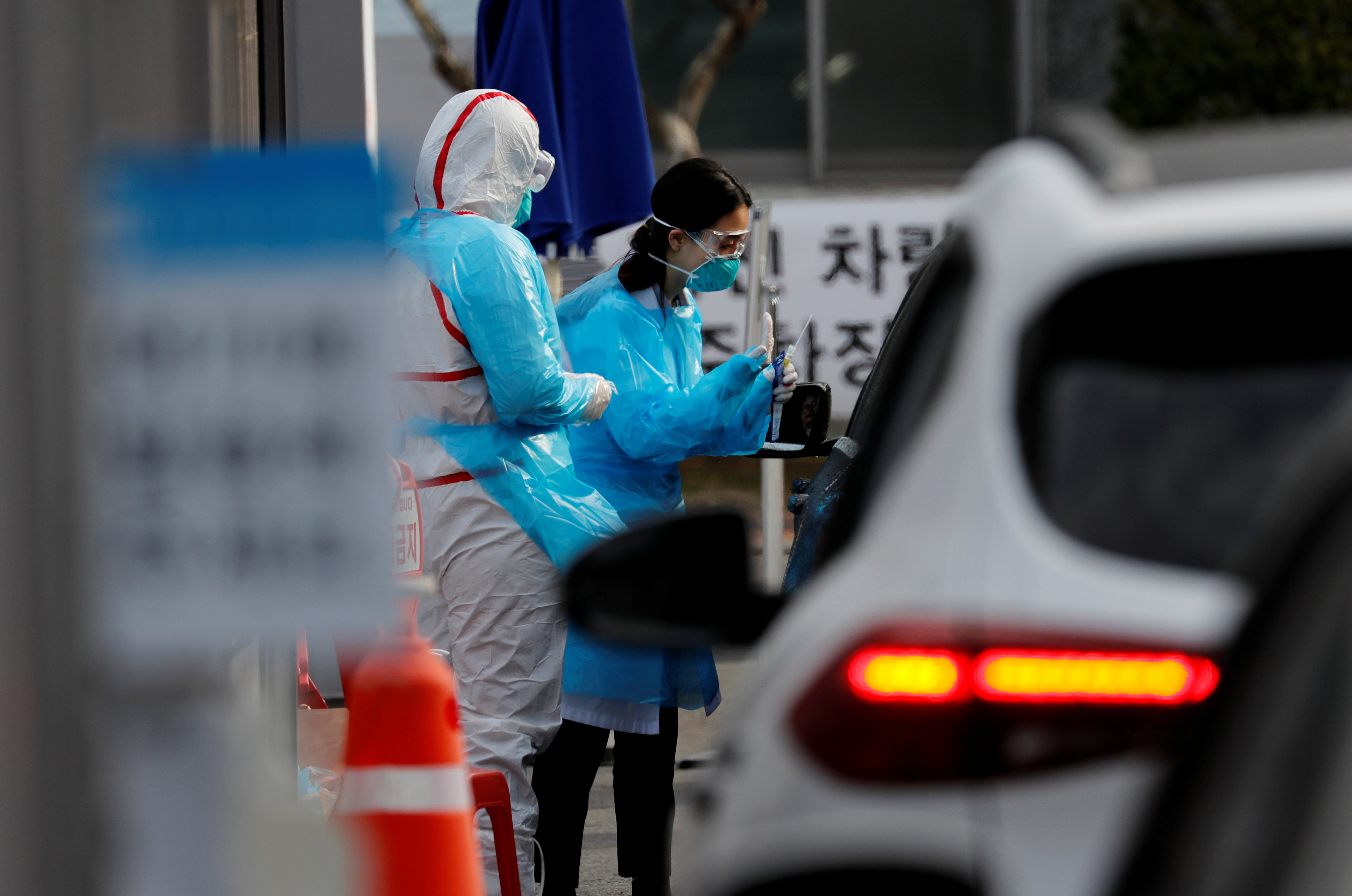 Un miembro del personal médico con equipo de protección se prepara para tomar muestras de un visitante en un auto en un centro de pruebas en Daegu, Corea del Sur, el 3 de marzo de 2020. (REUTERS/Kim Kyung-Hoon)