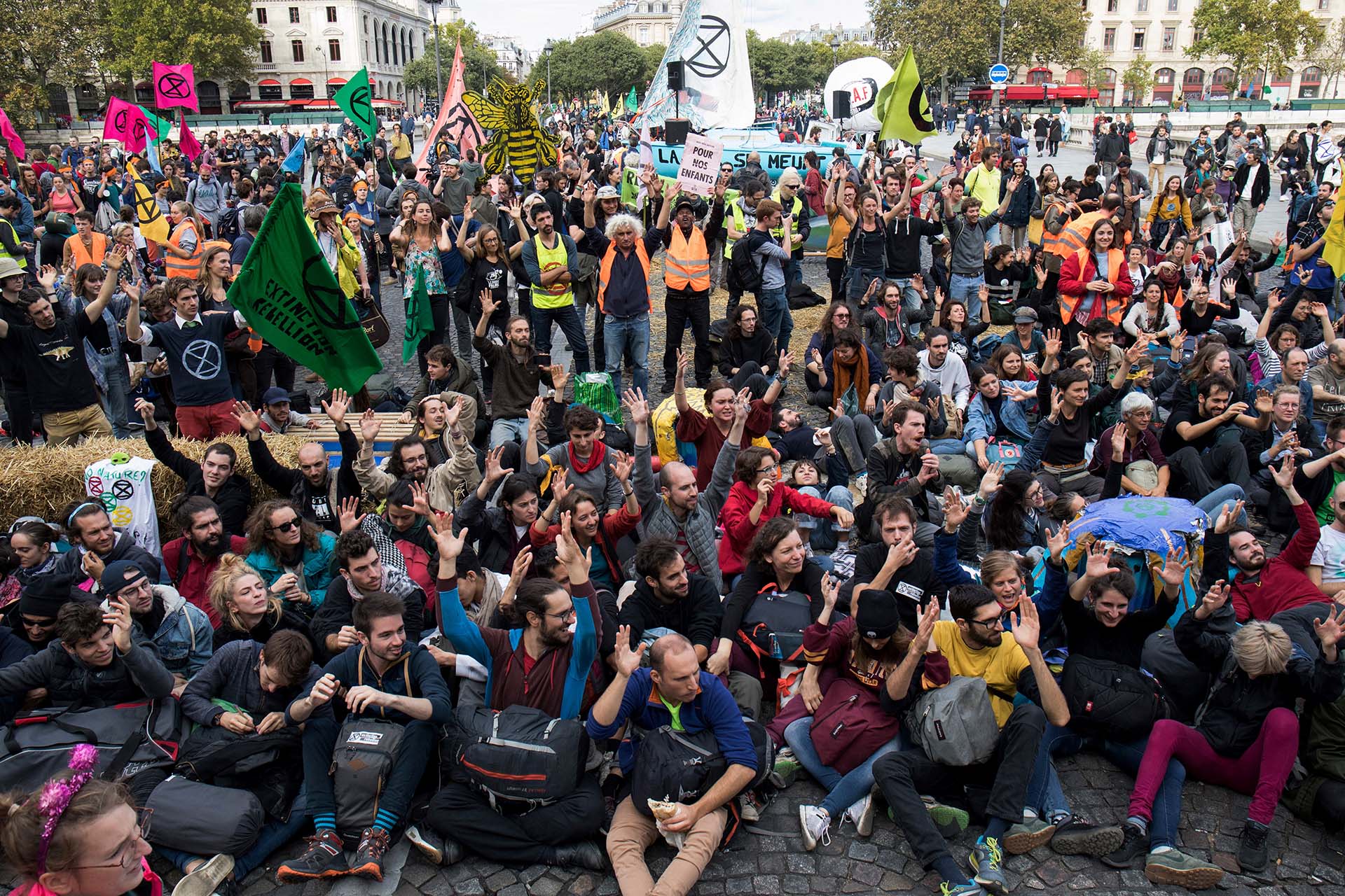 Los manifestantes se sientan en el suelo para bloquear el puente Pont au Change durante una manifestación convocada por el grupo activista del cambio climático Extinction Rebellion, el 7 de octubre de 2019 frente a la Conciergerie en París. (AFP)