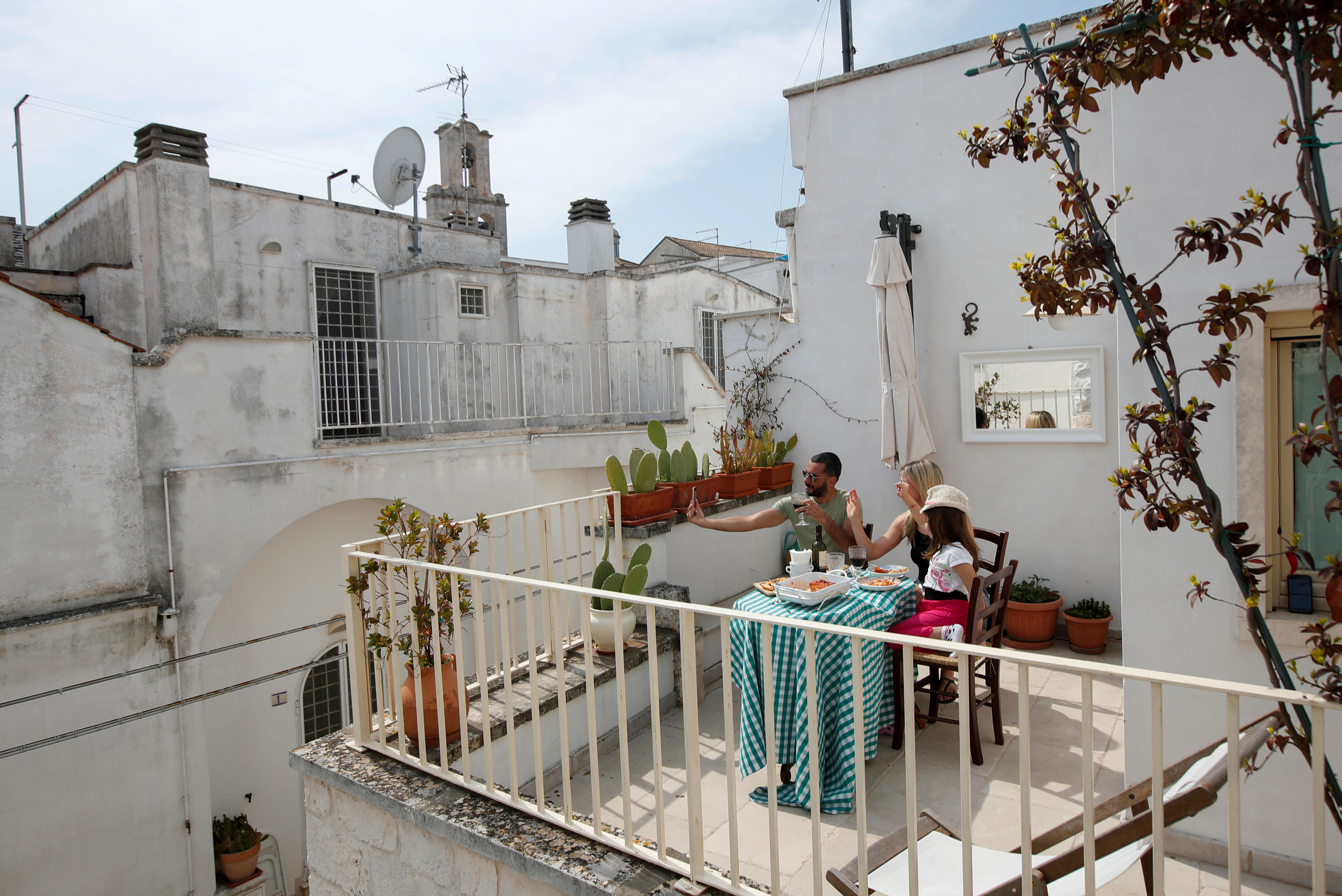 Una familia almuerza en la terraza de su casa mientras hablan con familiares en Cisternino, en el sur de Italia (REUTERS/Alessandro Garofalo)