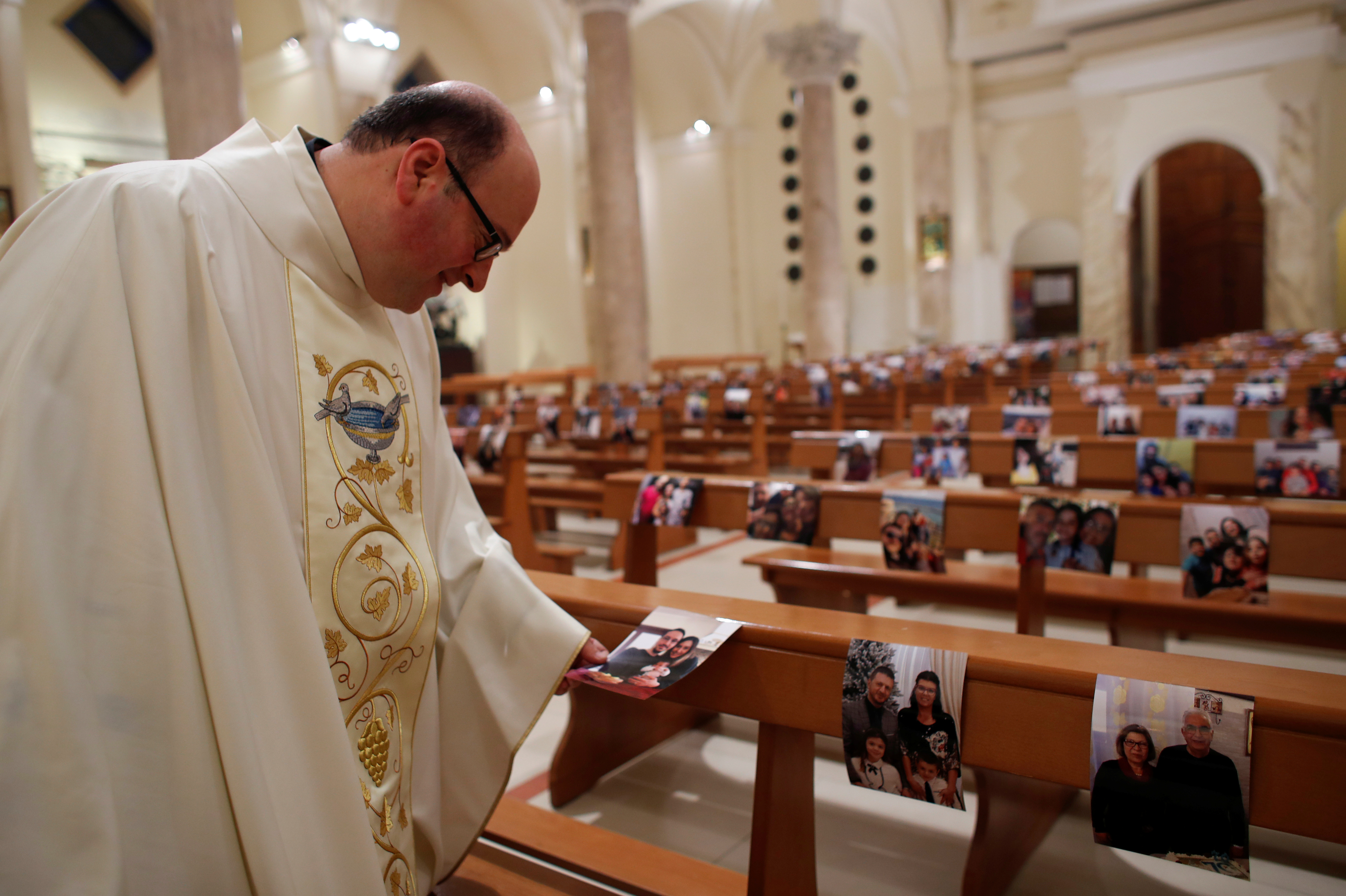 ITALIA - El padre Don Giancarlo Ruggieri observa las fotografías de miembros de la congregación de Porto San Giorgio, ciudad azotada por el COVID-19, el nuevo coronavirus, en la jornada de Pascuas