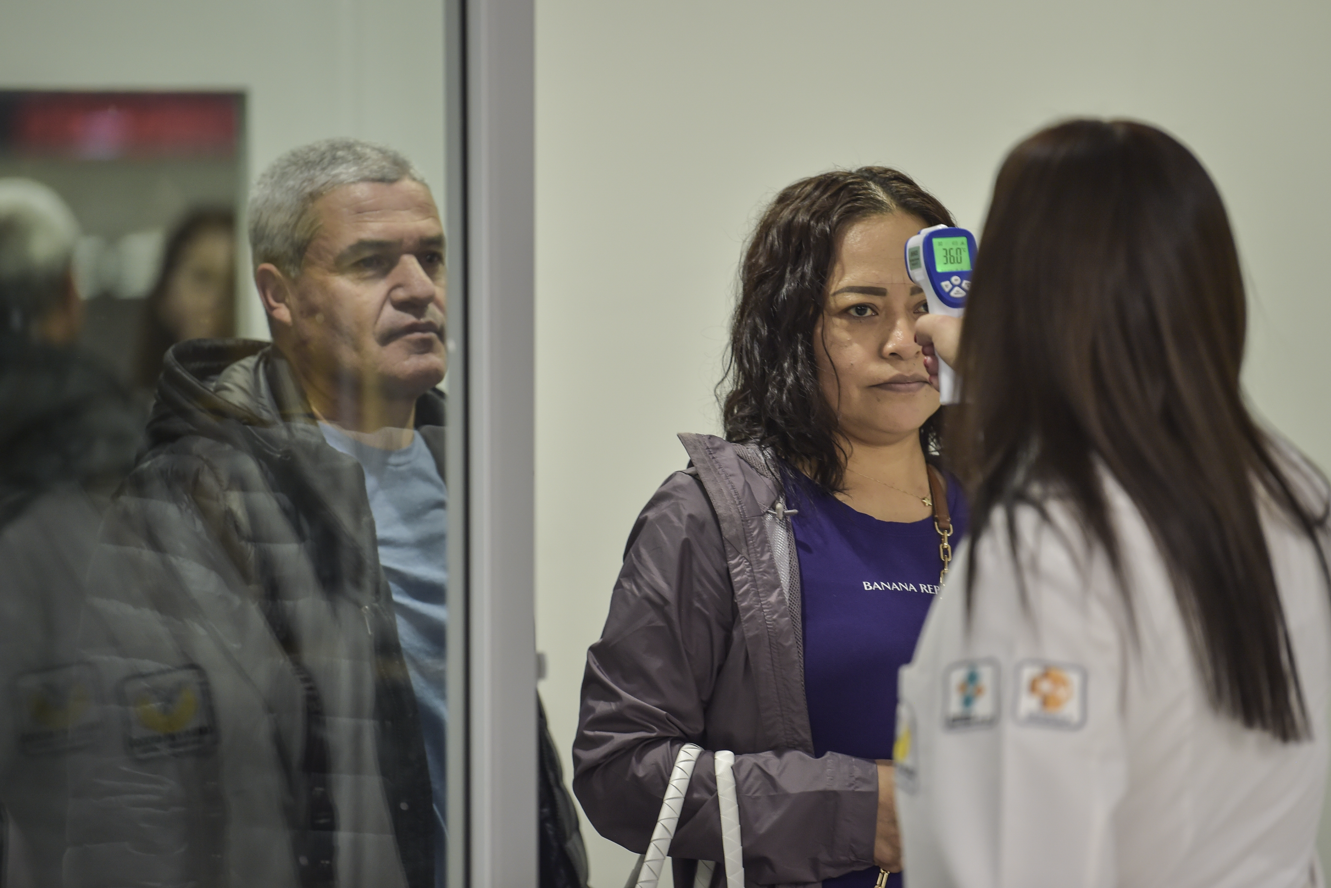 El personal de salud internacional verifica la temperatura de un pasajero como medida preventiva frente a la pandemia mundial de coronavirus COVID-19, en el aeropuerto internacional Benito Juárez en la Ciudad de México, el 13 de marzo de 2020.