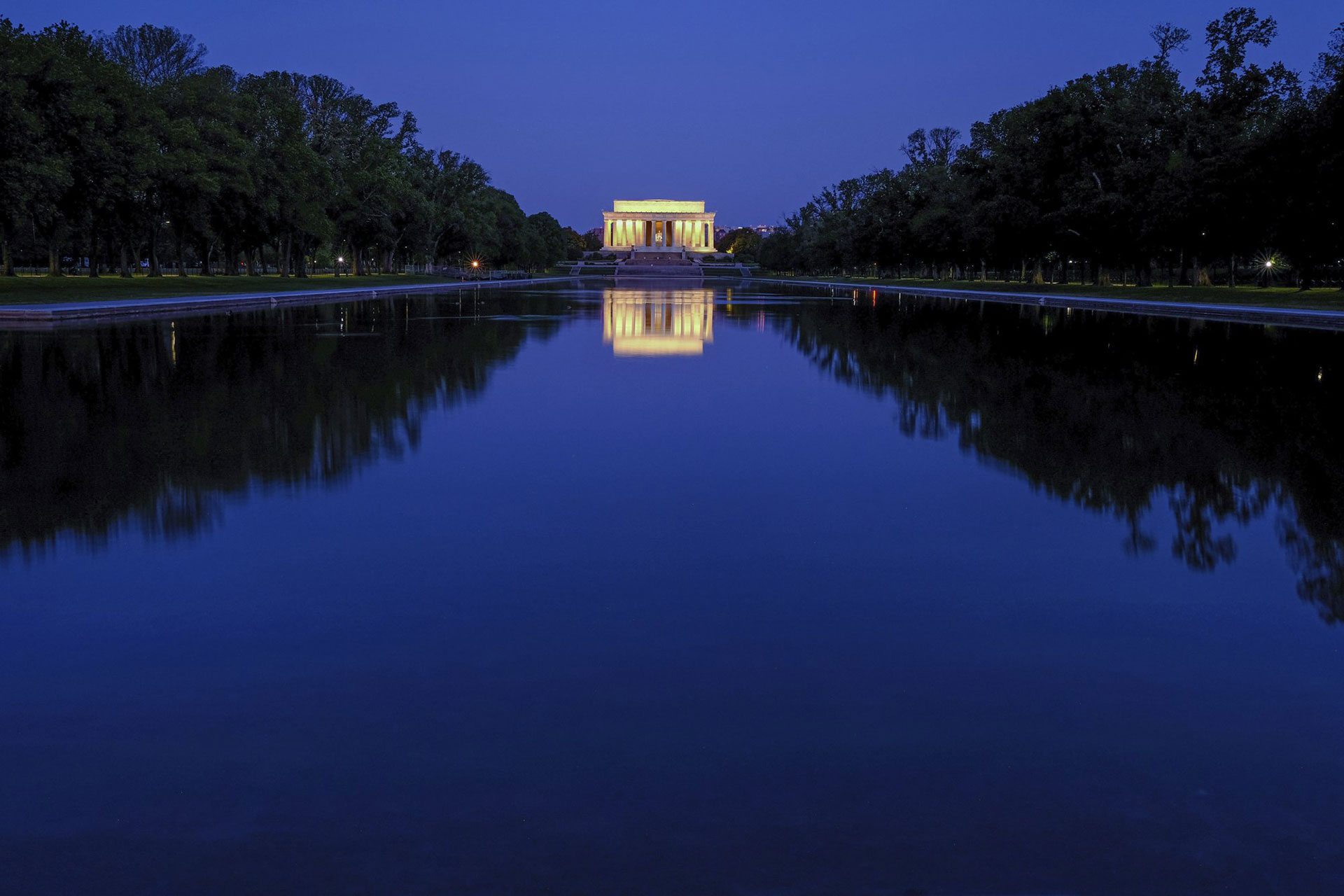 El Lincoln Memorial se refleja en las tranquilas aguas de la piscina reflectante en el National Mall en Washington, EEUU, antes del amanecer del miércoles 29 de abril de 2020. (Foto AP / J. David Ake)