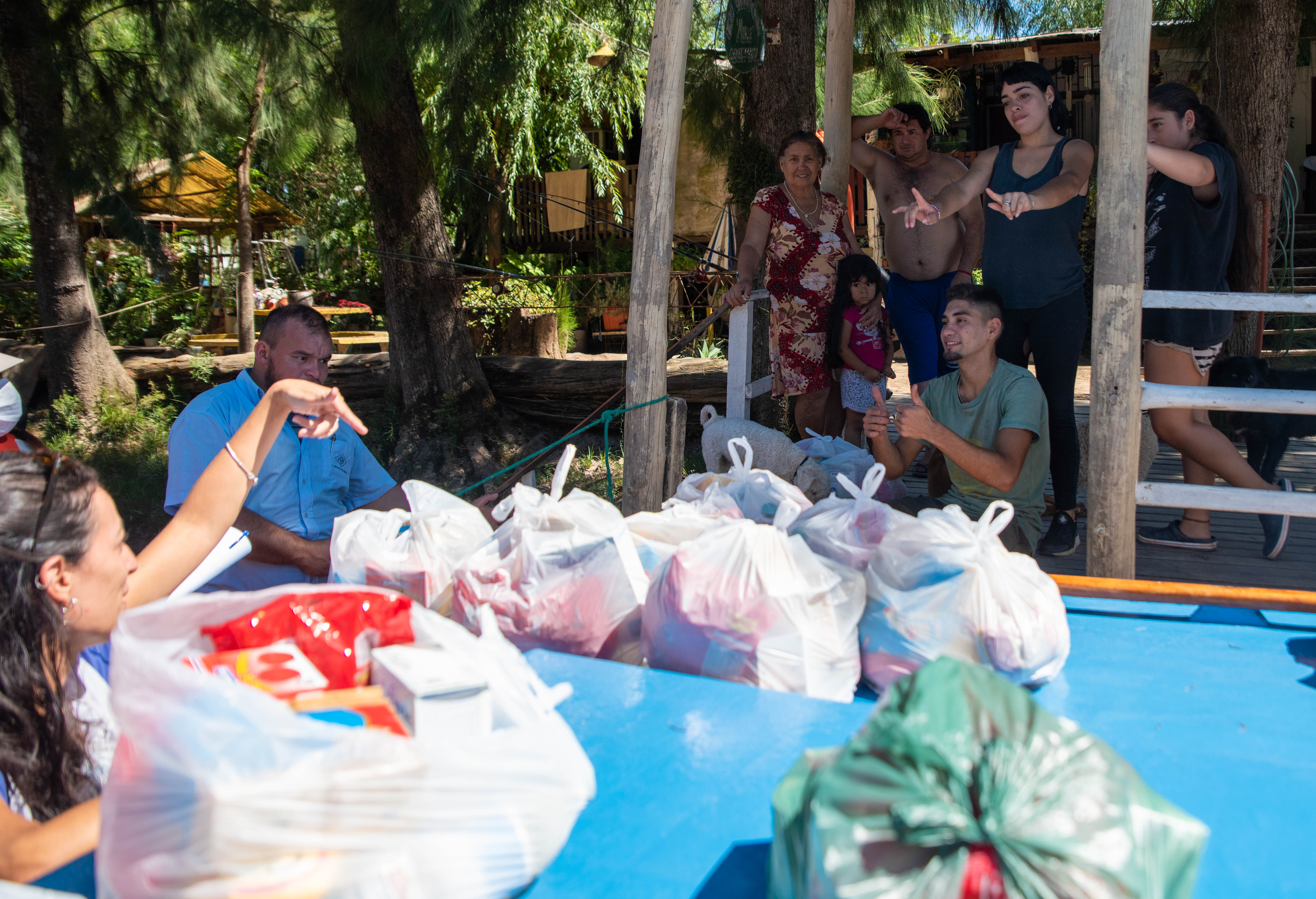Los docentes se despiden de la familia de uno de sus alumnos después de entregarle los kits alimenticios. (Foto: Franco Fafasuli)